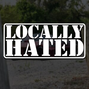 Könnte beinhalten: Ein rechteckiger Vinyl-Aufkleber mit dem weißen Text LOCALLY HATED in einer fetten Serifenschrift. Die Beschriftung ist in zwei Zeilen innerhalb eines schwarzen Rahmens angeordnet und erzeugt ein kontrastreiches Design für glatte Oberflächen.