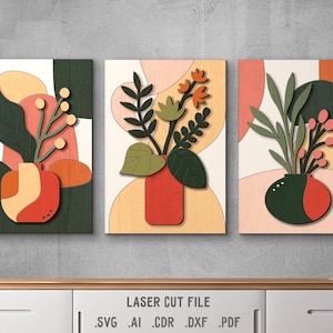 Puede incluir: Tres paneles de pared de madera cortados con láser con diseños florales abstractos. Cada panel presenta un jarrón con flores y hojas en tonos de verde, rojo y naranja sobre un fondo de melocotón, crema y marrón.