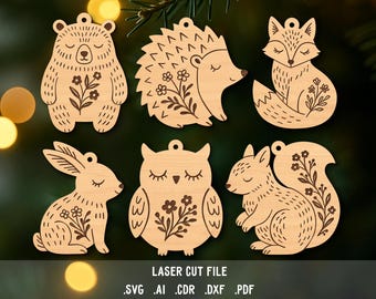 May include: Wooden laser-cut ornaments featuring a bear, hedgehog, fox, rabbit, owl, and squirrel. Each animal has floral details. The text "LASER CUT FILE" and file type extensions are at the bottom.