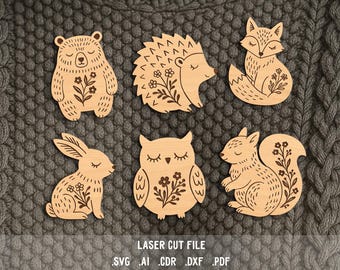 Puede incluir: Formas de animales de madera cortadas con láser, incluyendo un oso, un erizo, un zorro, un conejo, un búho y una ardilla. Cada animal tiene un diseño floral y ojos cerrados. El texto "LASER CUT FILE" y las extensiones de tipo de archivo están en la parte inferior.