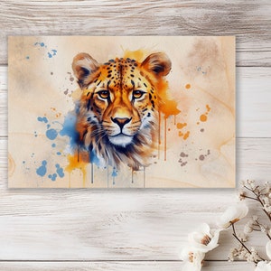 Könnte beinhalten: Ein Aquarellbild eines Gepardenkopfes mit orangefarbenen, gelben und blauen Farbstichen im Hintergrund.