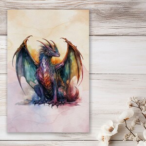 May include: A watercolor painting of a purple and green dragon with its wings spread out. The dragon is sitting on a cloud with a pink and purple background.