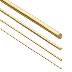 May include: Four brass rods of varying thicknesses are arranged diagonally against a white background. The rods have a smooth, polished surface and a warm, golden color. The rods are cylindrical and appear to be made of solid metal.