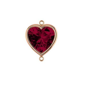 May include: A heart-shaped pendant with a deep red gemstone center and a gold-colored frame. The pendant has two small loops for attaching to a chain or other jewelry components. The gemstone has a faceted surface.