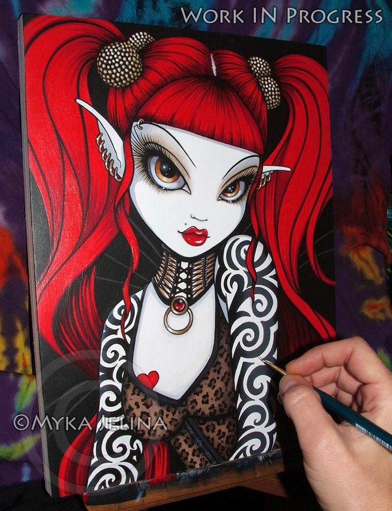 May include: A painting in progress of a fantasy character with red hair, black and white tattoos, and a leopard print top. The character has large eyes and red lips. The painting is on a canvas and is being worked on with a paintbrush.