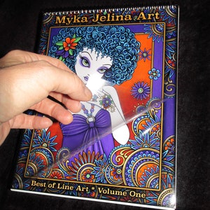 Może przedstawiać: Kolorowa okładka książki z kobietą o niebieskich włosach i fioletowej sukience. Okładka ma wz&oacute;r paisley i tekst "Myka Jelina Art Best of Line Art * Volume One".