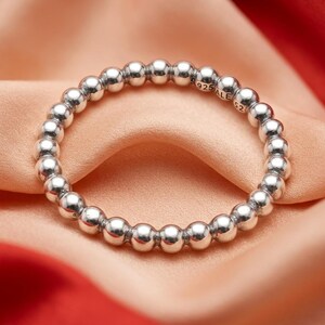May include: A sterling silver ring composed of a continuous band of polished, uniform metal spheres. The inner surface of the band features the engraved text 925 ALE 52, indicating the metal purity and size. The ring has a bright, reflective finish.