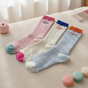 Könnte beinhalten: Ein Set aus drei Keramikbechern mit gesprenkelter, matter Oberfläche. Die Becher sind in Creme-, Hellgrau- und Dunkelgrautönen gehalten. Jeder Becher hat ein schlichtes, minimalistisches Design.