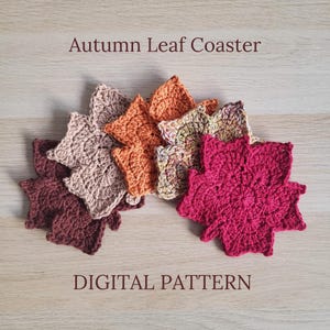 May include: A set of six crocheted leaf coasters in various autumn colours, including red, orange, brown, and beige. The coasters are arranged in a semi-circle on a wooden surface. The text "Autumn Leaf Coaster" and "DIGITAL PATTERN" is visible in the image.
