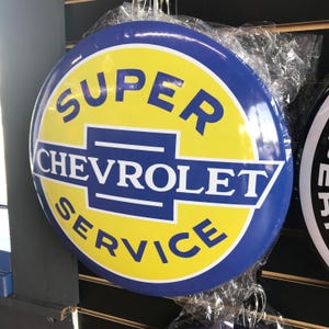 Puede incluir: Letrero redondo vintage de Chevrolet Super Service. El letrero presenta un centro amarillo con texto azul y un borde azul. El texto dice "SUPER CHEVROLET SERVICE" en letras blancas en negrita.