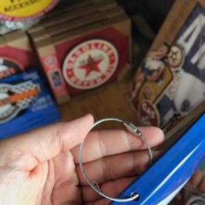 Puede incluir: Un letrero de metal azul con un lazo de alambre plateado para colgar. El letrero tiene una estrella blanca y el texto "Gas Oil" en &eacute;l.