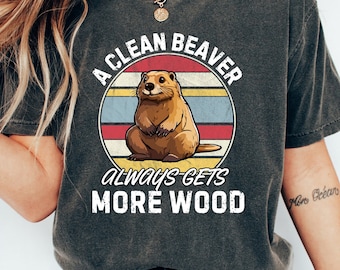 May include: A charcoal grey t-shirt with a vintage-style graphic of a beaver. The graphic says "A Clean Beaver Always Gets More Wood".