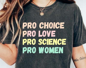 Könnte beinhalten: Ein dunkelgraues T-Shirt mit dem Text "PRO CHOICE PRO LOVE PRO SCIENCE PRO WOMEN", der in bunten Buchstaben gedruckt ist.