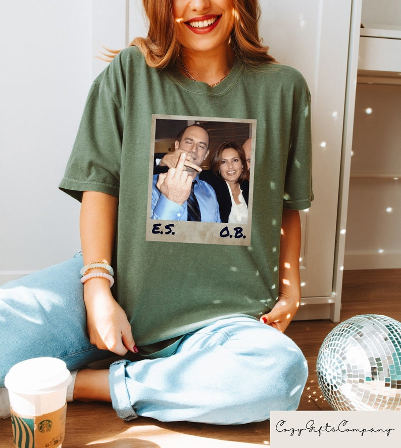 May include: A green t-shirt with a photo of two people. The photo is in a white frame with the text "E.S." and "O.B." written below it.