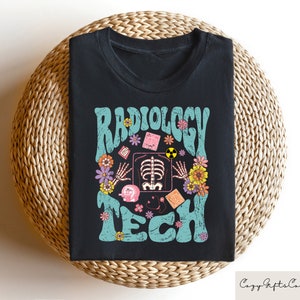 May include: Black t-shirt with a teal and white graphic that says "Radiology Tech" with a stylized x-ray image and flowers.