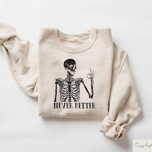 May include: A beige sweatshirt with a black skeleton graphic and the text "Never Better".
