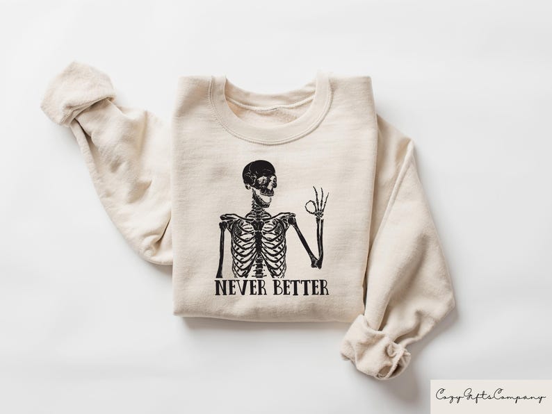 May include: A beige sweatshirt with a black skeleton graphic and the text "Never Better".