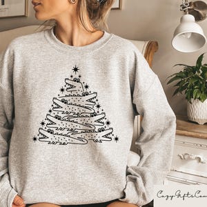 May include: A gray sweatshirt with a black and white graphic of alligators stacked to form a Christmas tree. The graphic includes a star at the top of the tree.