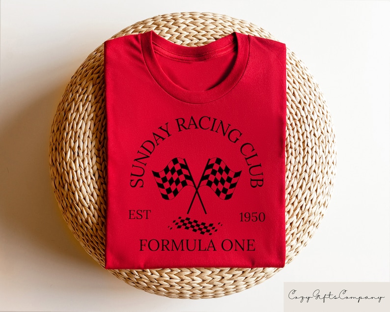 Puede incluir: Camiseta roja con un gr&aacute;fico negro que dice "Sunday Racing Club Est. 1950 Formula One" con un dise&ntilde;o de bandera a cuadros.