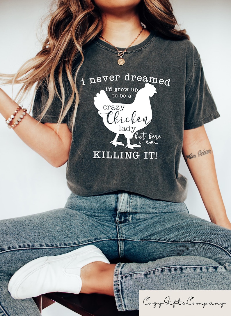 May include: A grey t-shirt with a white graphic of a chicken and the text "i never dreamed i'd grow up to be a crazy Chicken lady but here i am... KILLING IT!"