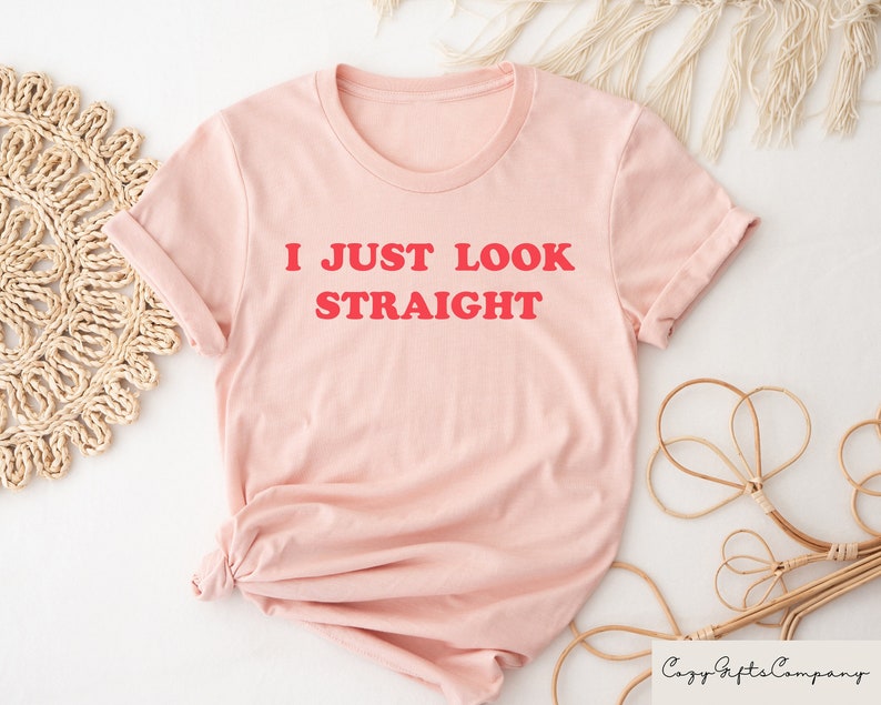 May include: A pink t-shirt with the text "I JUST LOOK STRAIGHT" in red.