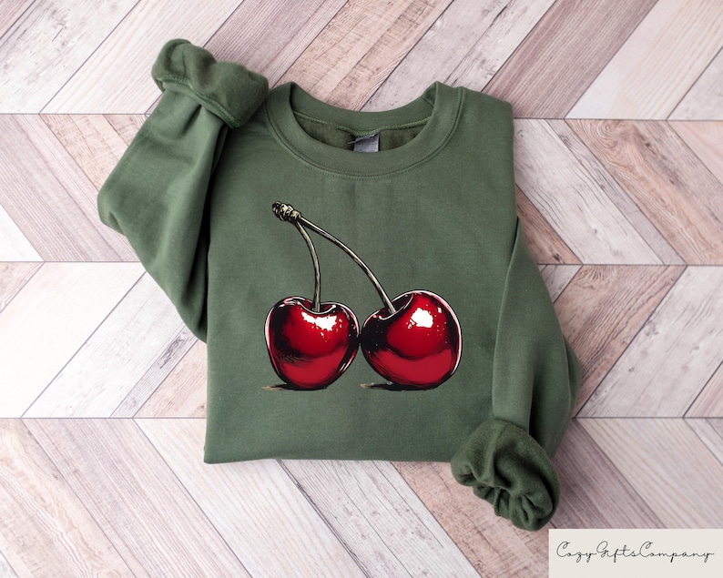 May include: A green sweatshirt with a graphic of two red cherries on the front.