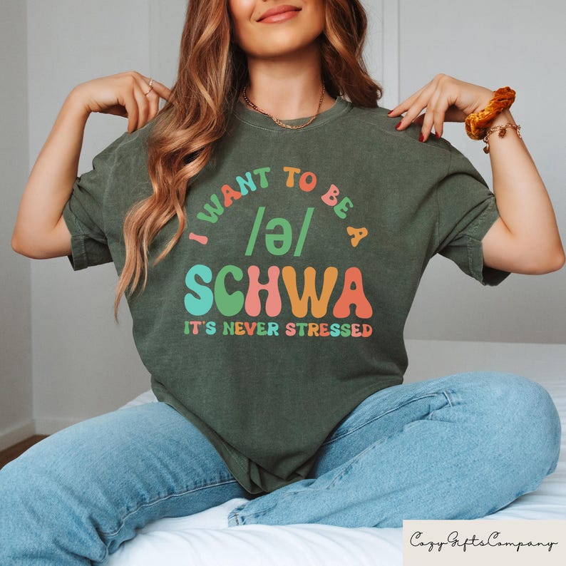 May include: A green t-shirt with the text "I want to be a /ə/ SCHWA It's never stressed" in colorful, retro-style lettering.