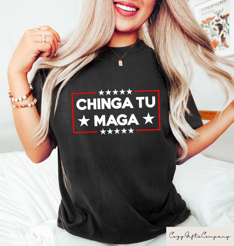 K&ouml;nnte beinhalten: Schwarzes T-Shirt mit dem Text "CHINGA TU MAGA" in wei&szlig;en Buchstaben in einem roten rechteckigen Rahmen, mit wei&szlig;en Sternen dar&uuml;ber und darunter. Das Shirt hat einen Rundhalsausschnitt.