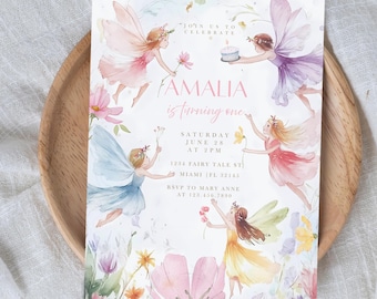 May include: A whimsical invitation featuring watercolor illustrations of fairies in pastel colors. The text reads "FAMALIA is turning one" with event details. Floral accents and a wooden tray complete the design, perfect for a child's birthday celebration.