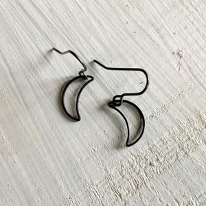 May include: A pair of black crescent moon earrings made of wire.