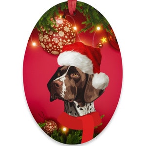 May include: Oval Christmas ornament featuring a German Shorthaired Pointer wearing a Santa hat and red scarf. The dog is brown and white with a red background, festive decorations, and a red ribbon for hanging.