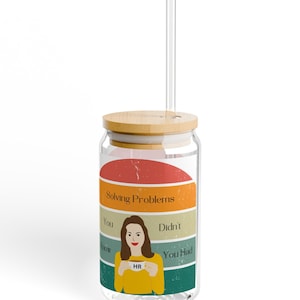 Puede incluir: Una lata de vidrio con tapa de bambú y una pajita. La lata tiene un gráfico de estilo retro con el texto "Solving Problems" y una imagen de dibujos animados de una persona sosteniendo un cartel que dice "HR".