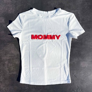 May include: White short-sleeved t-shirt with the word "MOMMY" in red raised letters.