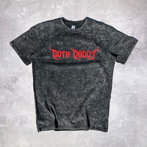 May include: A black acid wash t-shirt with the red text "GOTH DADDY" in a gothic font. The shirt has a crew neck and short sleeves. The fabric has a mottled, textured appearance.