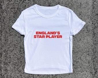 May include: White t-shirt with red text that says "England's Star Player".