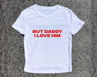 Puede incluir: Top blanco corto con texto rojo que dice "But Daddy I Love Him".