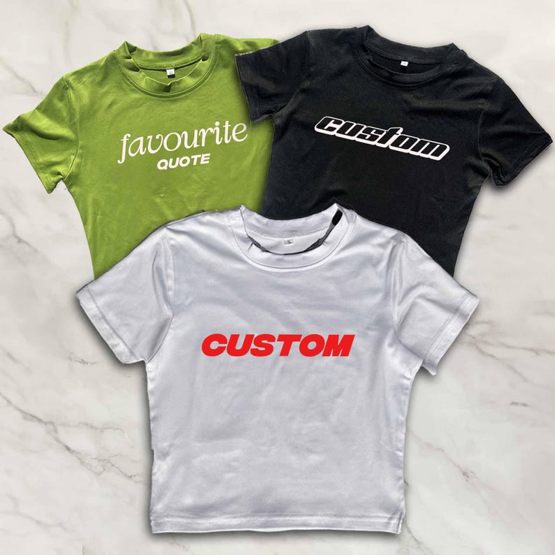 Puede incluir: Tres camisetas recortadas con diferentes dise&ntilde;os. Una es verde con el texto "favourite quote", otra es negra con el texto "custom" en blanco, y otra es blanca con el texto "CUSTOM" en rojo.