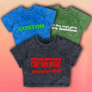 May include: Three acid-wash crop tops in blue, green, and charcoal. The blue top has the word "CUSTOM" in green. The green top reads "all the cool girls are lesbians" in white. The charcoal top says "YOUR WORDS OR IMAGE printed here" in red.