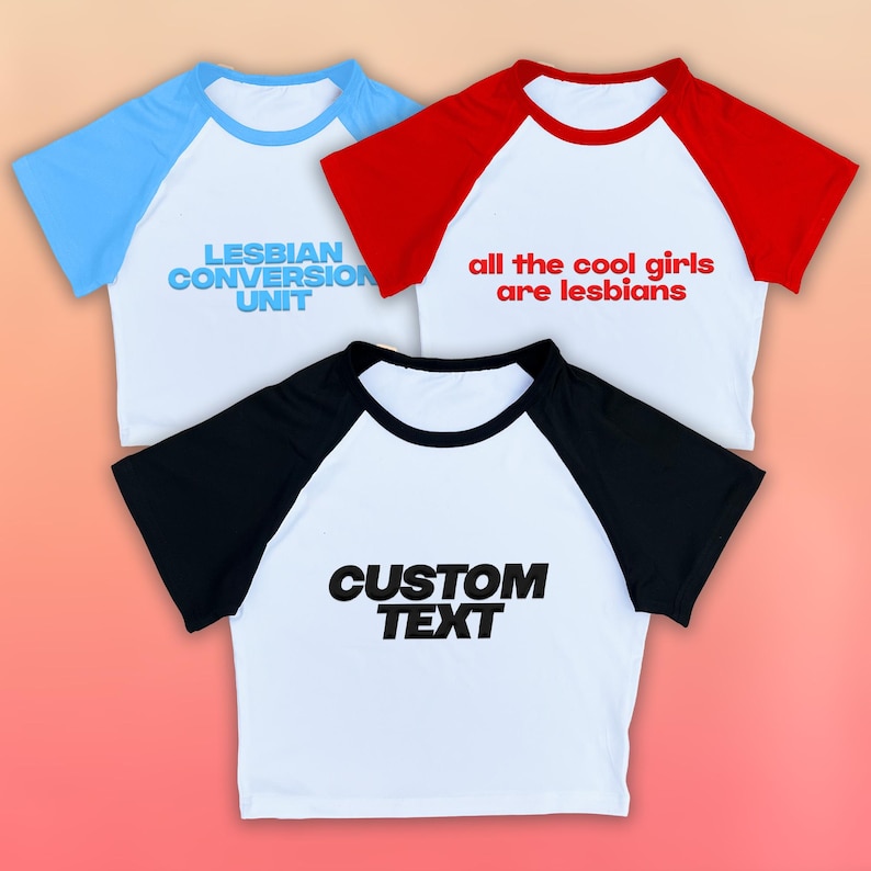 May include: Three white raglan t-shirts with different colored sleeves and text. One has light blue sleeves and reads "LESBIAN CONVERSION UNIT." Another has red sleeves and reads "all the cool girls are lesbians." The third has black sleeves and reads "CUSTOM TEXT."