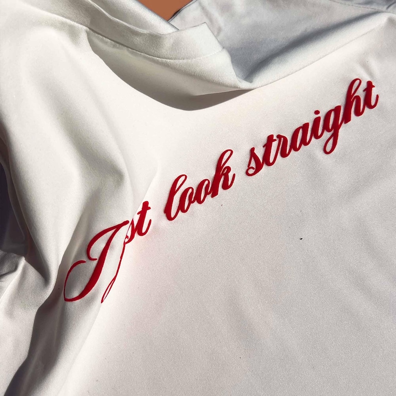 May include: White t-shirt with the text "I't look straight" in red cursive lettering.