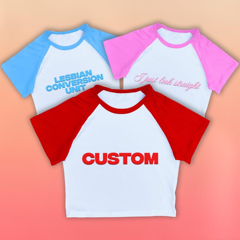 May include: Three baseball-style shirts with white bodies and colored sleeves. One shirt has blue sleeves and the text "LESBIAN CONVERSION UNIT". Another has pink sleeves and the text "I just look straight". The third has red sleeves and the text "CUSTOM".