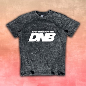 Puede incluir: Una camiseta gris oscuro con un efecto lavado a la piedra. El texto blanco "JUST HERE FOR THE DNB" está impreso en el pecho. La camiseta tiene cuello redondo y mangas cortas. Una prenda casual.
