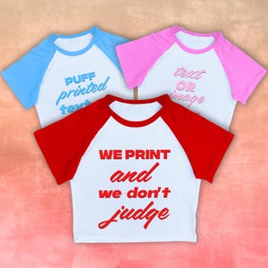 May include: Three raglan baseball t-shirts with white bodies and colored sleeves. One has blue sleeves with "PUFF printed text", another has pink sleeves with "text OR image", and the third has red sleeves with "WE PRINT and we don't judge".
