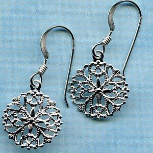 May include: A pair of silver dangle earrings with a delicate, intricate filigree design. The earrings are circular and feature a floral pattern.