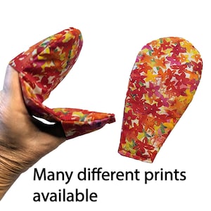 May include: Two floral print oven mitts. One is being held, showing the inside, and the other is displayed separately. The mitts have a red background with yellow, orange, and pink flower patterns. Text at the bottom reads "Many different prints available."