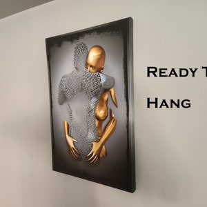 May include: A 3D wall art piece featuring two figures embracing. The figures are made of metal and painted in gold and silver. The artwork is ready to hang.