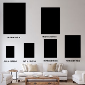 May include: A comparison of different sizes of black framed artwork displayed on a white wall above a white couch and a wooden coffee table. The measurements of each frame are listed below each frame.