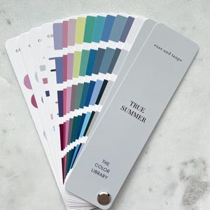 May include: A fan-shaped color swatch deck titled True Summer by The Color Library, featuring a light gray cover with the text rose and taupe. The deck displays a variety of color samples including shades of blue, green, pink, and purple.