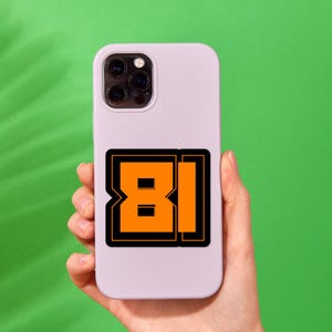 May include: A white phone case with a black and orange sticker that says "81" on it.