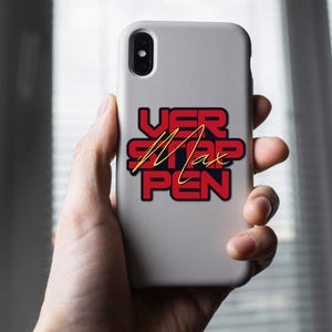 May include: A white phone case with a red and black sticker that says "VER STAP PEN" with the name "Max" written in gold lettering.